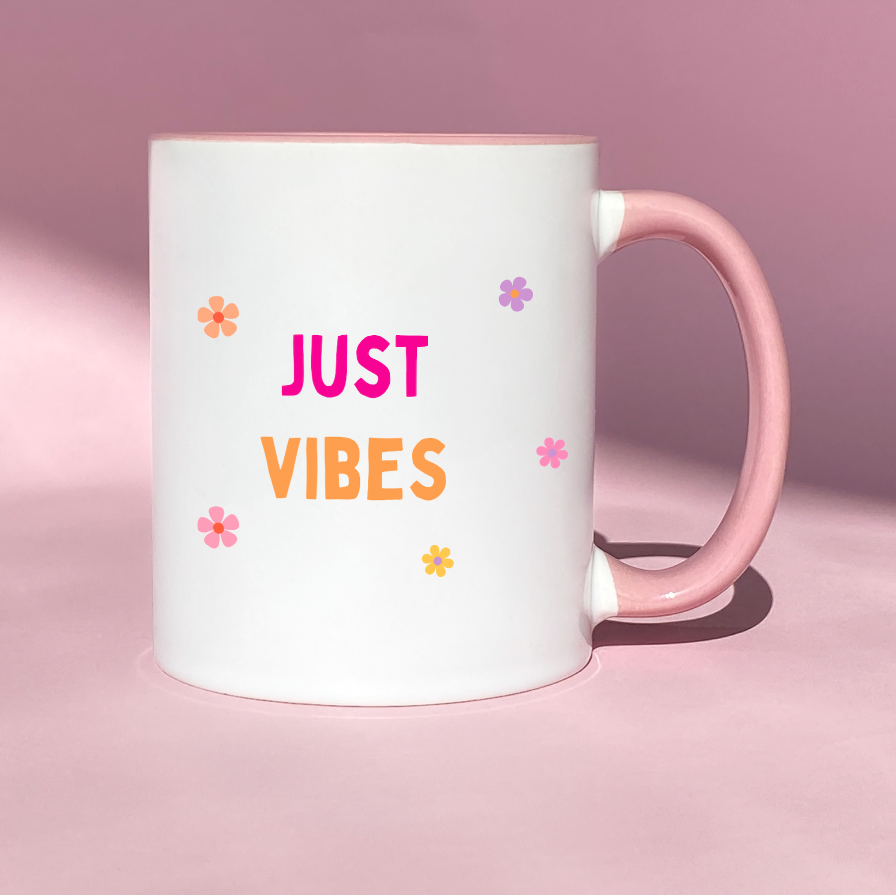 White ceramic mug with colorful flowers and the playful phrase 'No Fadhbs Just Vibes' in bold lettering.